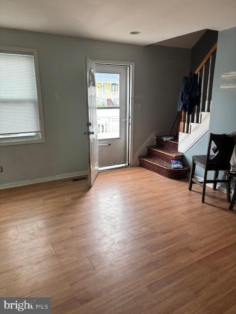 entryway with visible vents, baseboards, wood finished floors, and stairs