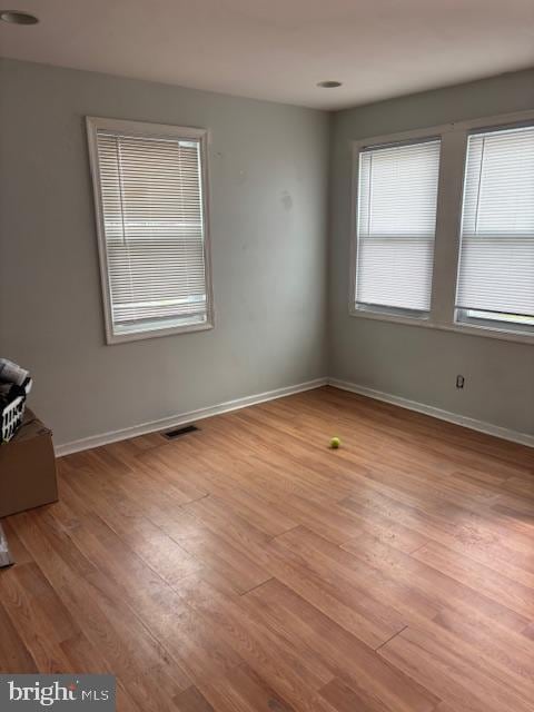 unfurnished room with light wood-style flooring, baseboards, and visible vents