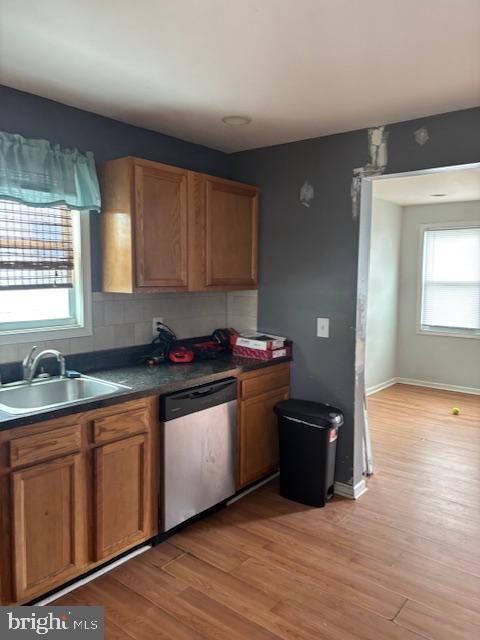 kitchen featuring stainless steel dishwasher, a wealth of natural light, light wood-style flooring, and a sink