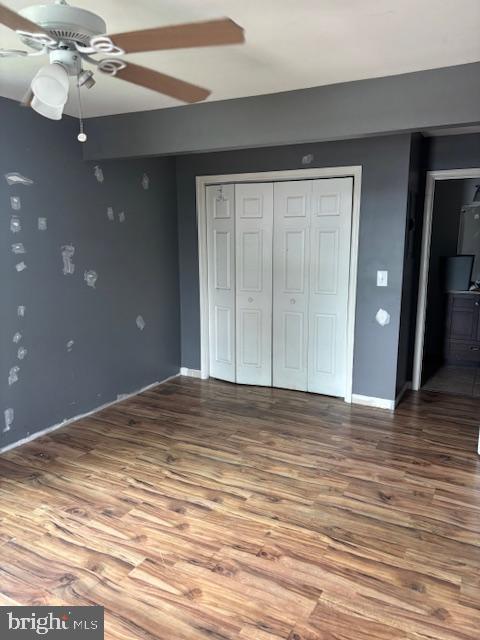 unfurnished bedroom with a closet, ceiling fan, and wood finished floors