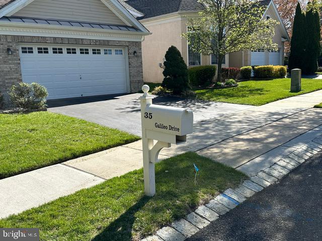 35 Galileo Dr, Cranbury, NJ 08512 - view of front of property featuring a front lawn, brick siding, a standing seam roof, and driveway
