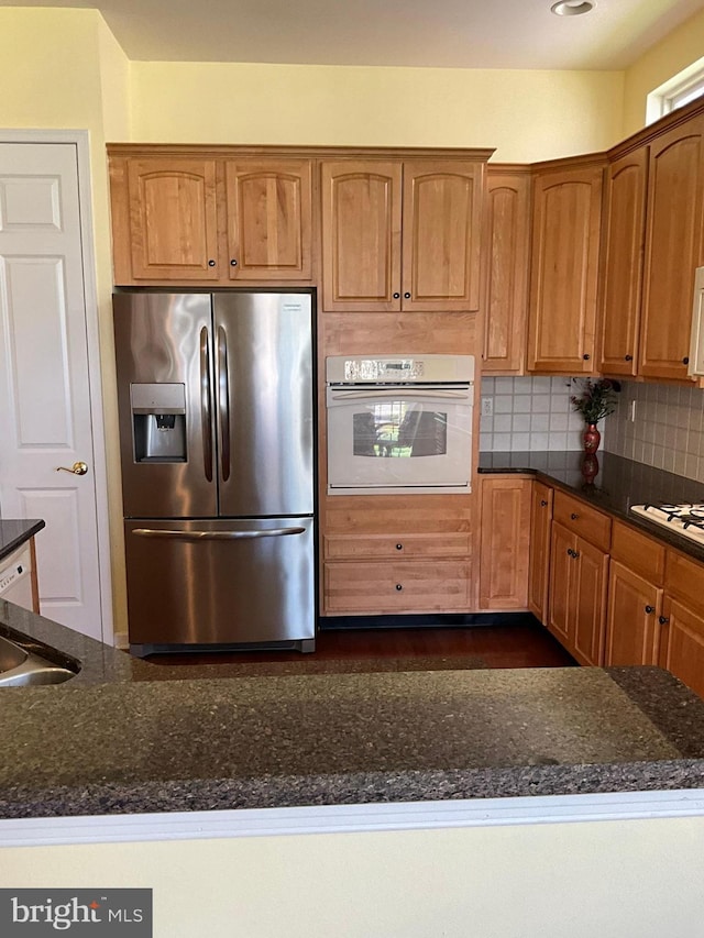 35 Galileo Dr, Cranbury, NJ 08512 - kitchen featuring brown cabinetry, dark stone counters, decorative backsplash, and white appliances