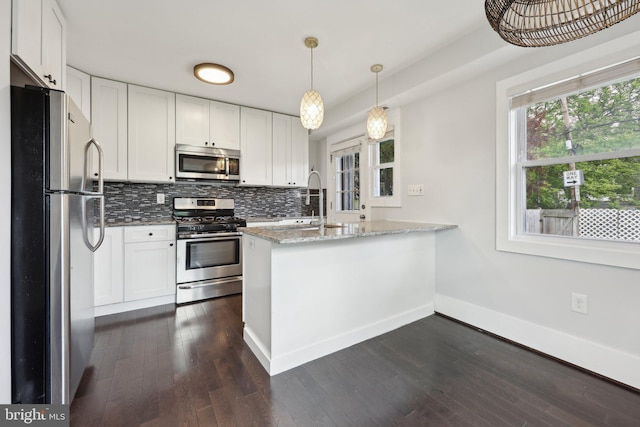 2026 Savannah Pl SE, Washington, DC 20020 - kitchen with dark wood finished floors, light stone counters, stainless steel appliances, a peninsula, and white cabinetry