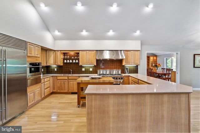 kitchen featuring a sink, a kitchen island, a warming drawer, wall chimney exhaust hood, and high end appliances