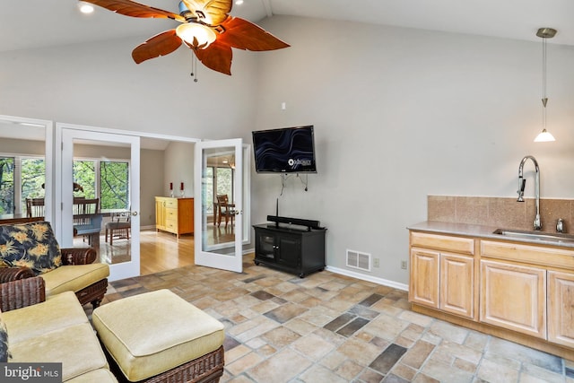 living room with stone finish flooring, ceiling fan, baseboards, visible vents, and high vaulted ceiling