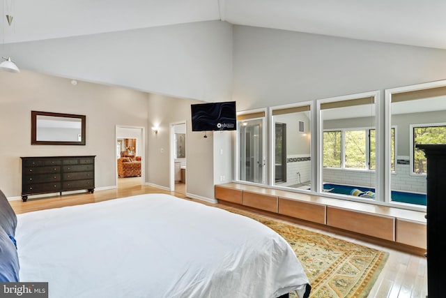 bedroom with baseboards, light wood-type flooring, connected bathroom, and high vaulted ceiling
