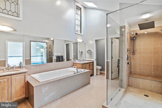 full bath featuring a shower stall, toilet, vanity, a garden tub, and a towering ceiling