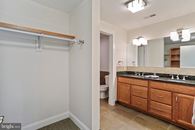 full bath with tasteful backsplash, double vanity, toilet, a sink, and visible vents