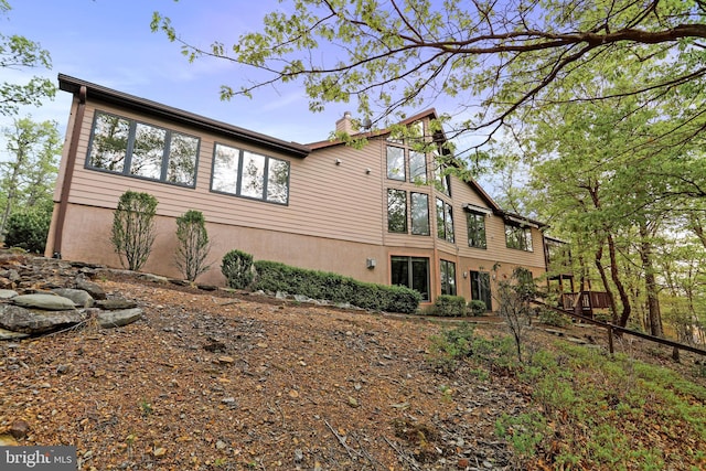 view of side of home with stucco siding and a chimney
