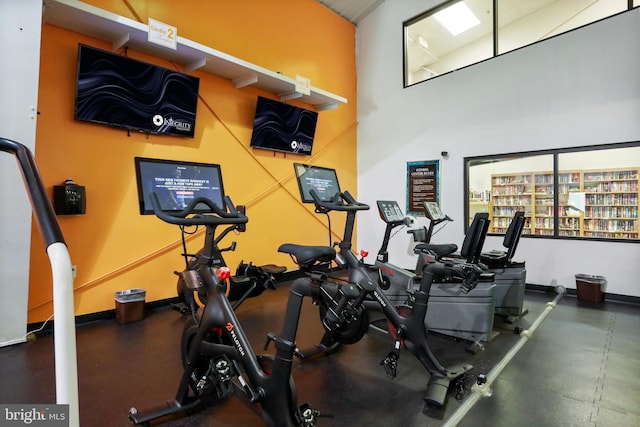 exercise room featuring a high ceiling and baseboards
