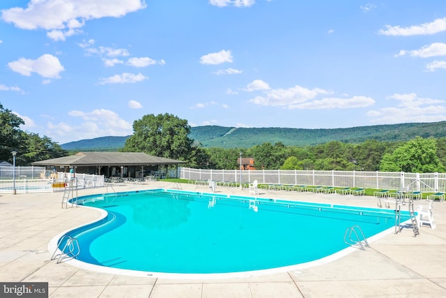 pool featuring a mountain view, a patio, and fence
