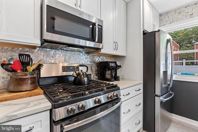1448 Sheridan St NW, Washington, DC 20011 - kitchen featuring stainless steel appliances, decorative backsplash, light stone counters, and white cabinetry