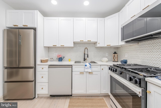 kitchen with a sink, dishwasher, light countertops, gas stove, and freestanding refrigerator