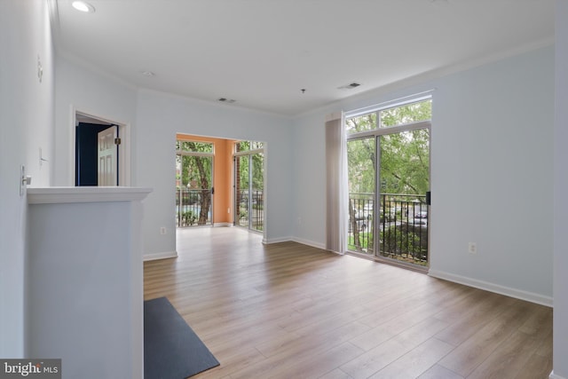 unfurnished living room featuring crown molding, a wealth of natural light, visible vents, and wood finished floors