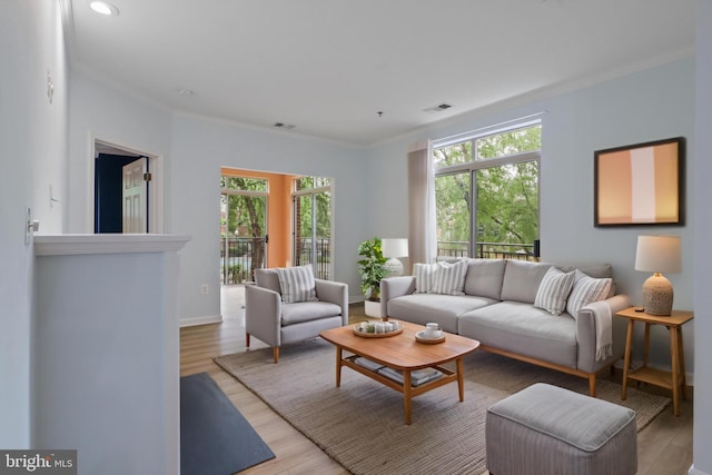 living room with ornamental molding, a wealth of natural light, light wood-type flooring, and visible vents