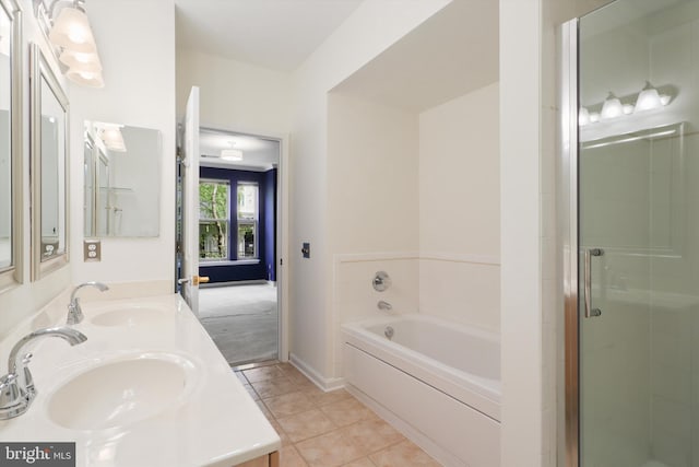 bathroom with tile patterned floors, a garden tub, double vanity, and a sink