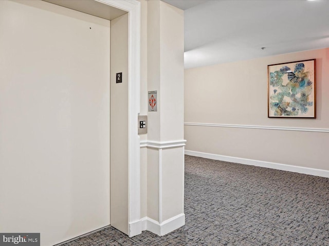 hall featuring carpet, baseboards, and elevator