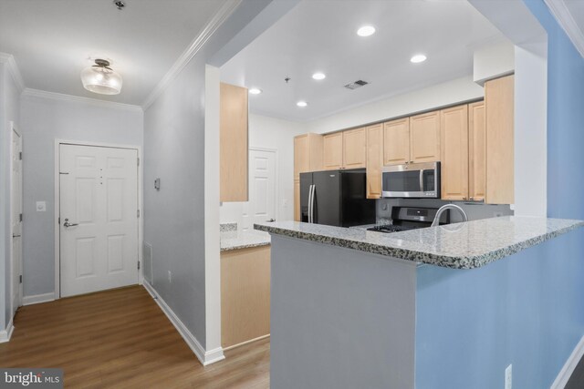 kitchen featuring a peninsula, light wood-style flooring, stainless steel appliances, light brown cabinets, and visible vents
