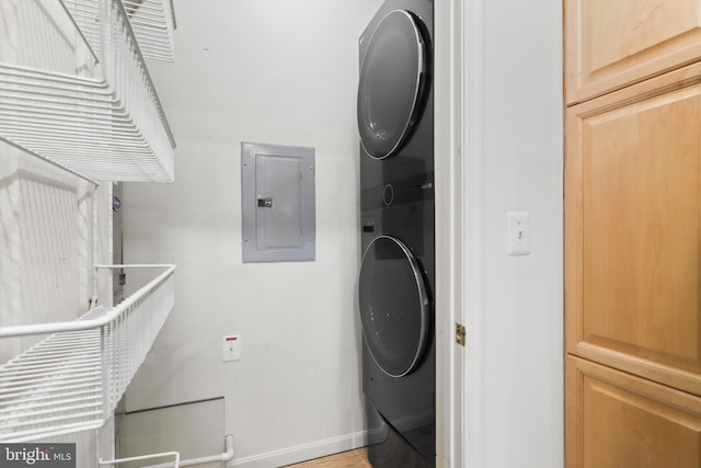 washroom featuring baseboards, stacked washing maching and dryer, laundry area, and electric panel