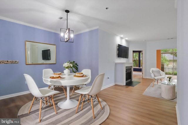 dining space featuring wood finished floors, ornamental molding, visible vents, baseboards, and a fireplace with flush hearth