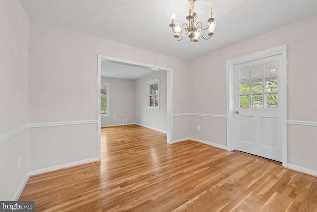 unfurnished dining area featuring a chandelier, light wood-style floors, and a healthy amount of sunlight