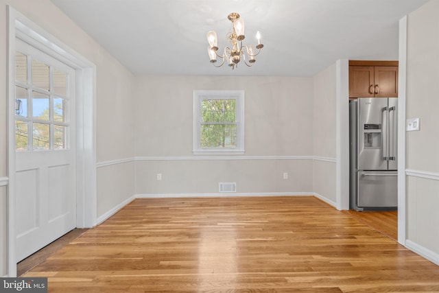 unfurnished dining area featuring a notable chandelier, light wood finished floors, visible vents, and baseboards