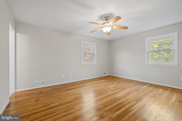 empty room with light wood-type flooring, baseboards, a ceiling fan, and visible vents