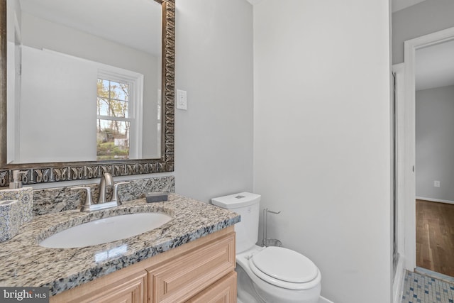 bathroom with vanity, baseboards, and toilet