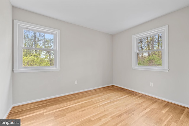 empty room featuring plenty of natural light, baseboards, and wood finished floors