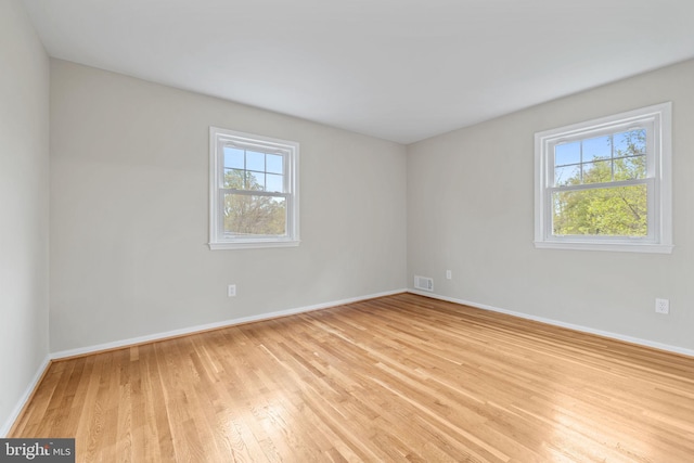spare room with visible vents, baseboards, and light wood finished floors