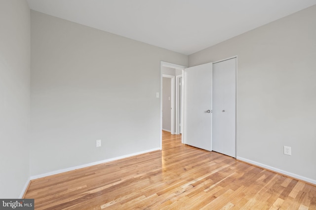 unfurnished bedroom with a closet, baseboards, and wood finished floors