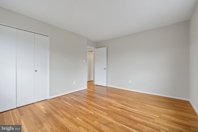 unfurnished bedroom featuring a closet, baseboards, and light wood-type flooring