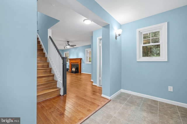interior space with a fireplace, a ceiling fan, baseboards, and stairway