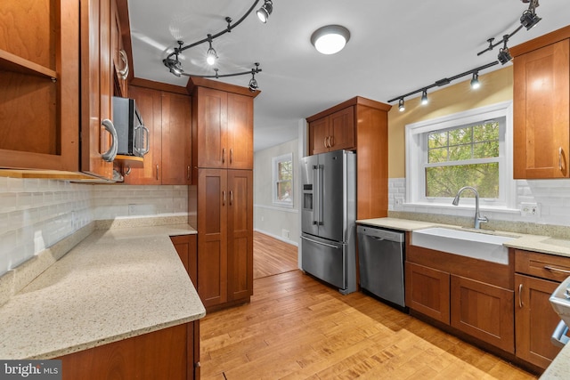 kitchen featuring track lighting, brown cabinets, a sink, and stainless steel appliances