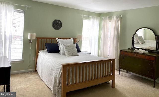 bedroom with baseboards, light colored carpet, and multiple windows