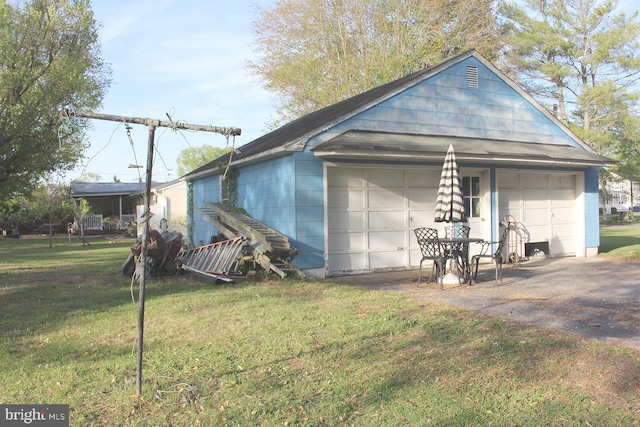 exterior space featuring a garage, an outbuilding, and a yard
