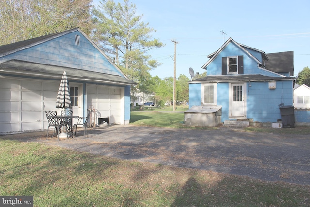 rear view of property with a lawn, entry steps, and a garage