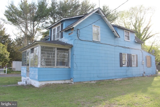 view of side of home with a lawn and a sunroom