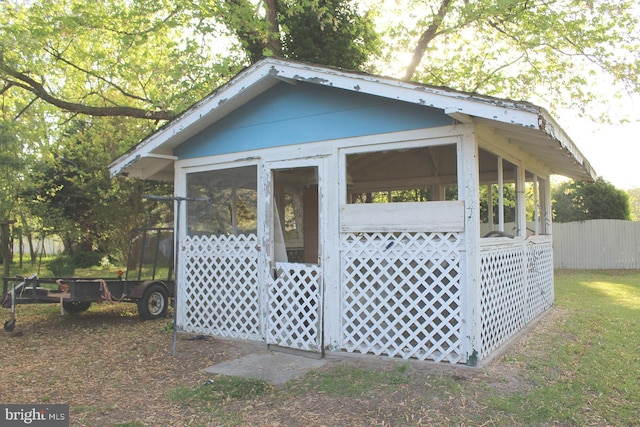 view of outbuilding featuring fence and a sunroom