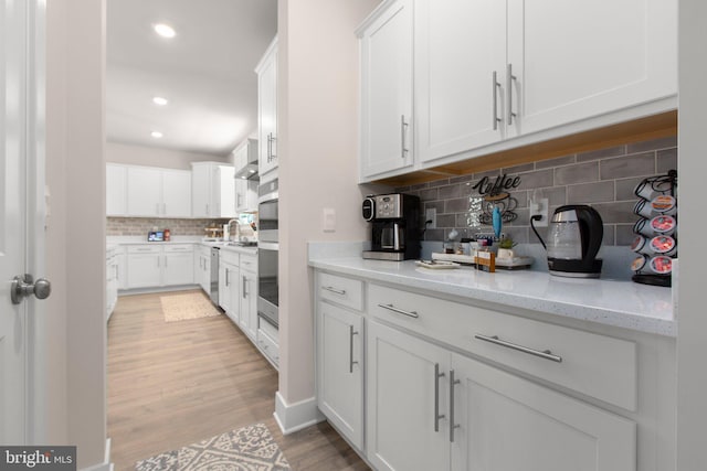 kitchen featuring recessed lighting, tasteful backsplash, light wood-style flooring, and white cabinetry