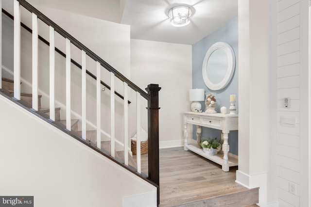 foyer featuring baseboards, wood finished floors, and stairway