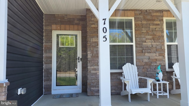 entrance to property with a porch and stone siding