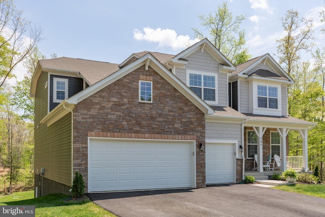 view of front of property featuring a shingled roof, stone siding, covered porch, and aphalt driveway