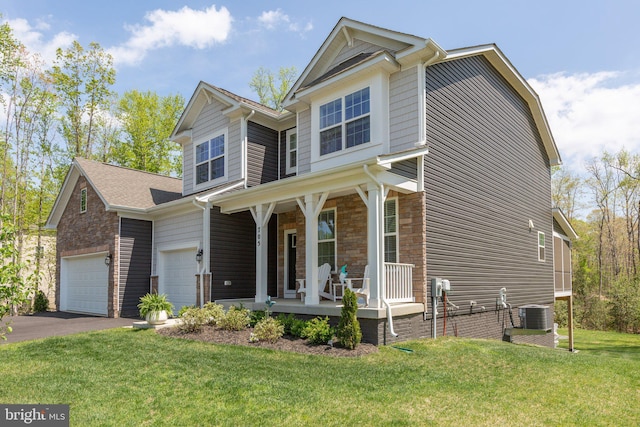 craftsman house with a front lawn, aphalt driveway, stone siding, covered porch, and a garage