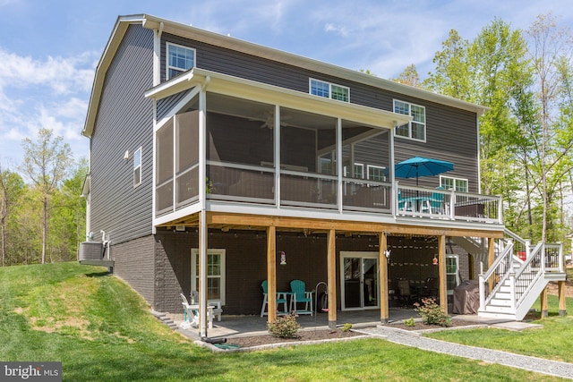 back of property with stairway, a patio area, a lawn, a sunroom, and a deck