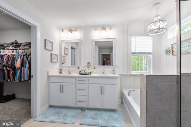 full bathroom featuring a walk in closet, a notable chandelier, a sink, and double vanity