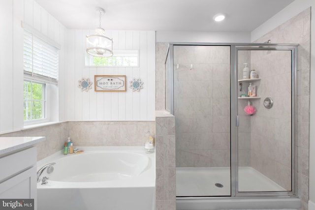 bathroom with a bath, a notable chandelier, vanity, and a stall shower