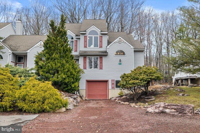 traditional home featuring a shingled roof, driveway, and an attached garage