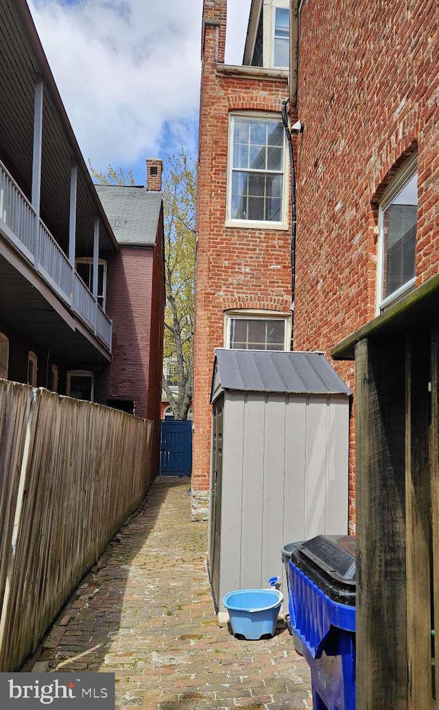 124 W Church St, Frederick, MD 21701 - view of side of home featuring brick siding, an outdoor structure, fence, and a storage unit