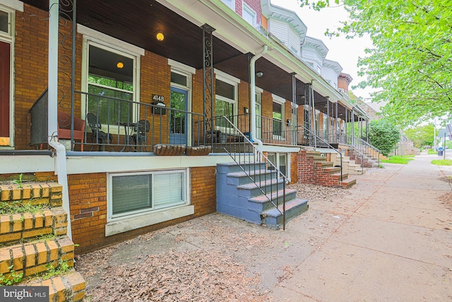 entrance to property featuring covered porch and brick siding